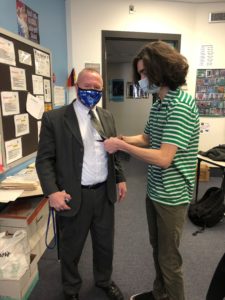 student cutting Roy Webb's necktie