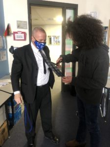 student cutting Roy Webb's necktie